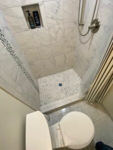 A view of the shower flooring and toilet seat