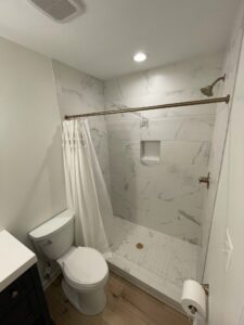 The white shower next to the toilet seat