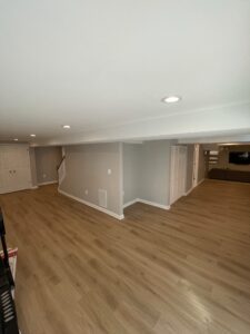 An empty basement room with wooden flooring