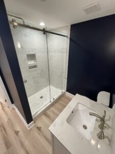 A glass shower in a dark blue bathroom